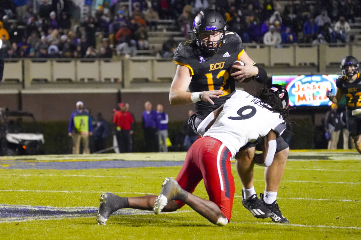 Nov 26, 2021; Greenville, North Carolina, USA; East Carolina Pirates quarterback Holton Ahlers (12) is stopped on his run by Cincinnati Bearcats cornerback Arquon Bush (9) during the second half at Dowdy-Ficklen Stadium. Mandatory Credit: James Guillory-USA TODAY Sports